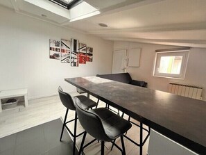 A modern kitchen with a long countertop, bar stools, and a skylight. - Comfortable Apartment In Downtown La Rochelle (La Rochelle)