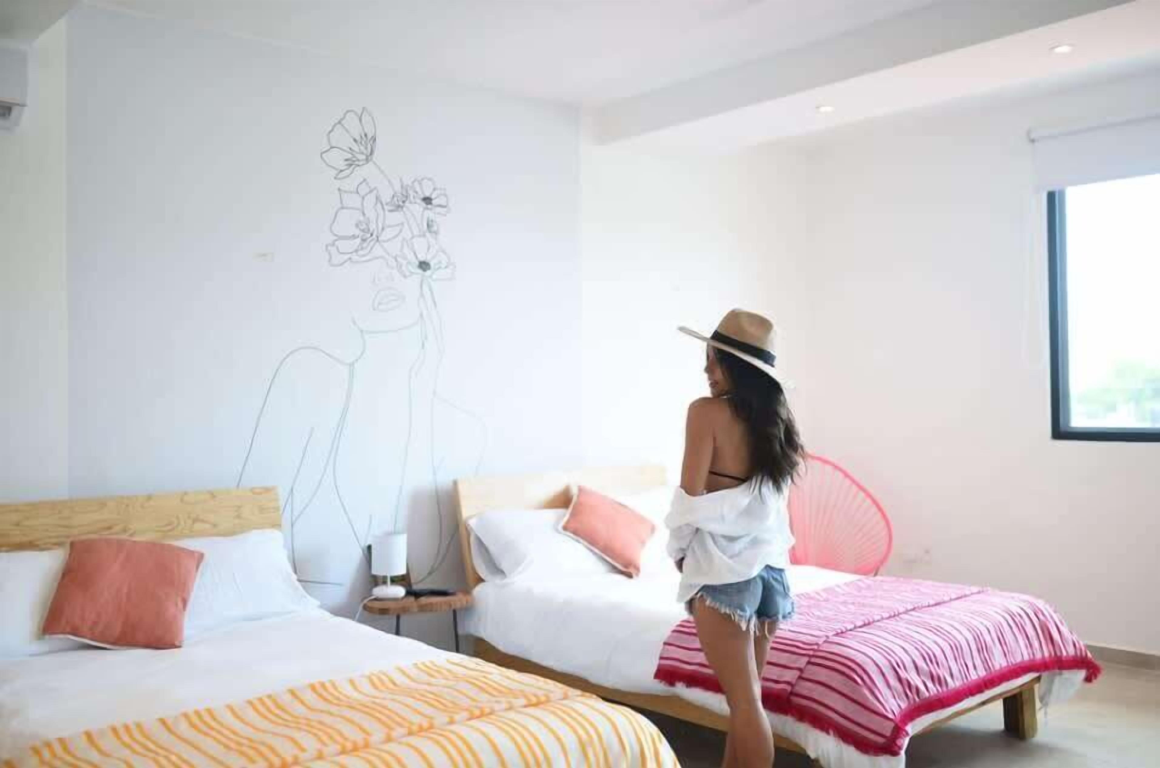 A modern hotel room with two beds, a large window, and a wall mural.