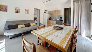 Un espace de vie compact comprenant un canapé, une table à manger, des chaises et un coin cuisine.