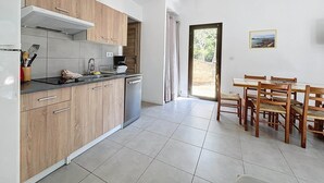 Une cuisine moderne avec des meubles en bois, un lave-vaisselle et un coin repas comprenant une table et des chaises.