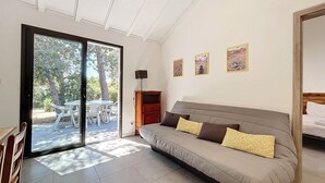 Une pièce moderne avec un canapé, une table à manger et des chaises, située devant une porte-fenêtre coulissante.