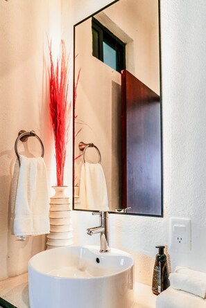 A bathroom with a white sink, a mirror, and two towels hanging on towel rings. - King Studio Walk to Beach + Rooftop Pool (Playa del Carmen)