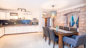A modern kitchen with white cabinets, a black countertop, and a dining area with a wooden table and chairs. - Beuatiful Villa with private pool for 8 people. (Veliki Vareski)