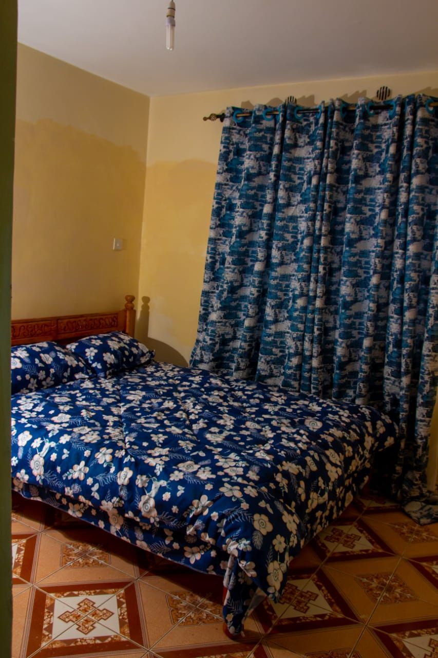 A room with a bed, curtains, and a patterned floor.