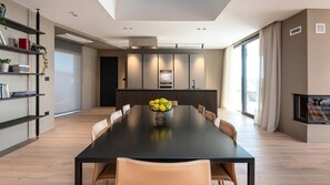 A modern dining area with a long table, chairs, and a fruit bowl. - Luxury Villa Aruna with pool (Štinjan)