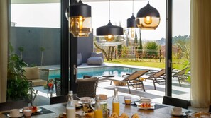 A poolside dining area with a view of a swimming pool, lounge chairs, and a table set for breakfast. - Luxury Villa Aruna with pool (Štinjan)