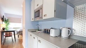 A compact kitchen with a microwave, toaster, and kettle on the counter, a sink, and cabinets. - Prince Street Studio 2 - Hopewell (Bristol)