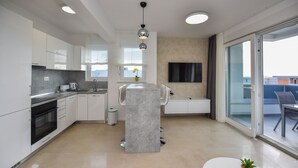 A modern kitchen with white cabinets, a built-in oven, and a central island with seating. - Mare Three-bedroom Apartments with Pool and Terrace (Novalja)
