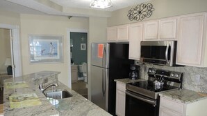 A kitchen with granite countertops, stainless steel appliances, and white cabinetry.