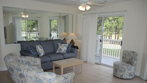 A living room with a grey sofa, matching armchairs, a wooden coffee table, and a ceiling fan. - Golf Course View Villa 3009 With Access to Golf Course and Outdoor Pool by Redawning (Calabash)
