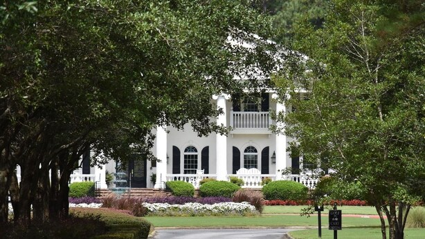 A white building with a symmetrical facade, a central entrance, and a small porch with steps leading up to it. - Ground Floor Studio 2503L in Brunswick Plantation Resort with Family Friendly Outdoor Pools Onsite by RedAwning (Calabash)
