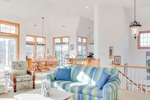 A spacious living area with a striped sofa, dining table, and chairs.