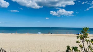 A beach with clear skies and a few people.