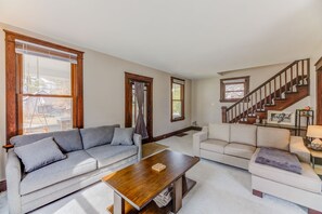 Ein geräumiges Wohnzimmer mit zwei Sofas, einem Holztisch und einer Treppe zu einer oberen Etage.