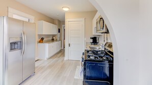 Een keuken met een koelkast, fornuis en witte kasten.