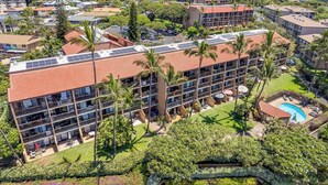 A multi-story hotel with a rooftop pool, surrounded by lush greenery and palm trees. - Exceptional Maui Vista Condo With Ocean Views (Kihei)