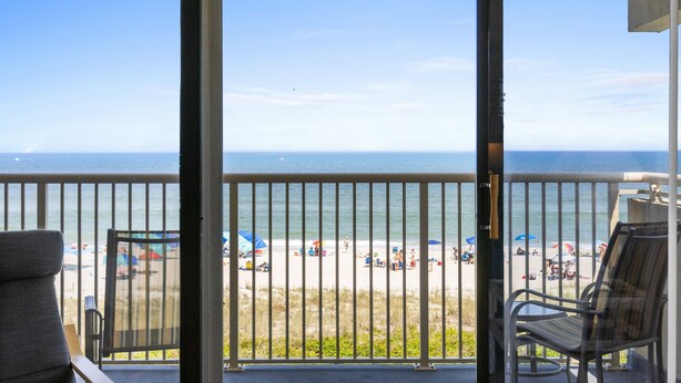 Un balcon donnant sur une plage, avec une chaise et une table.