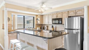 Une cuisine dotée d’un îlot central, d’appareils électroménagers en acier inoxydable et de meubles de rangement en bois clair.