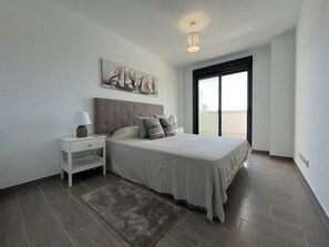 A modern bedroom with a large bed, a nightstand, a wall-mounted artwork, and a view through a large window. - CT 104   El Lagar de La Cala (Mijas)