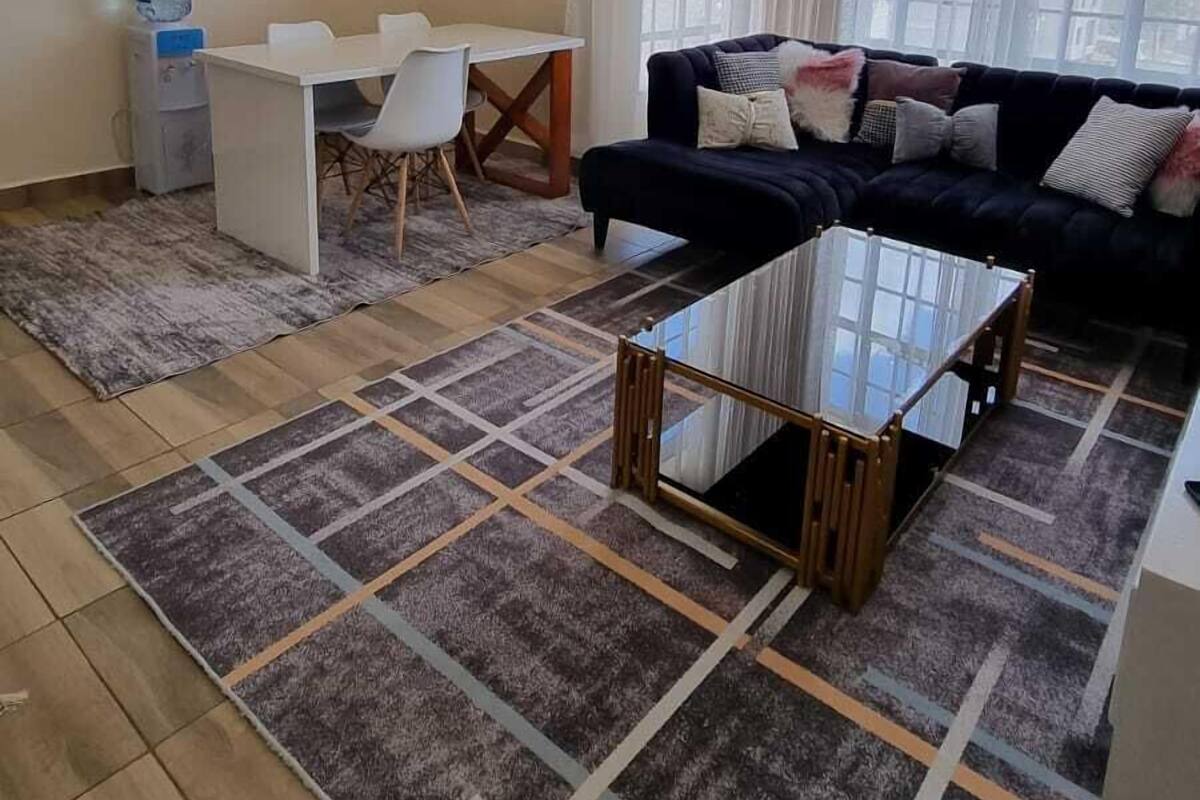 Un salon comprenant un canapé, une table basse, une table à manger avec des chaises et un distributeur d’eau.