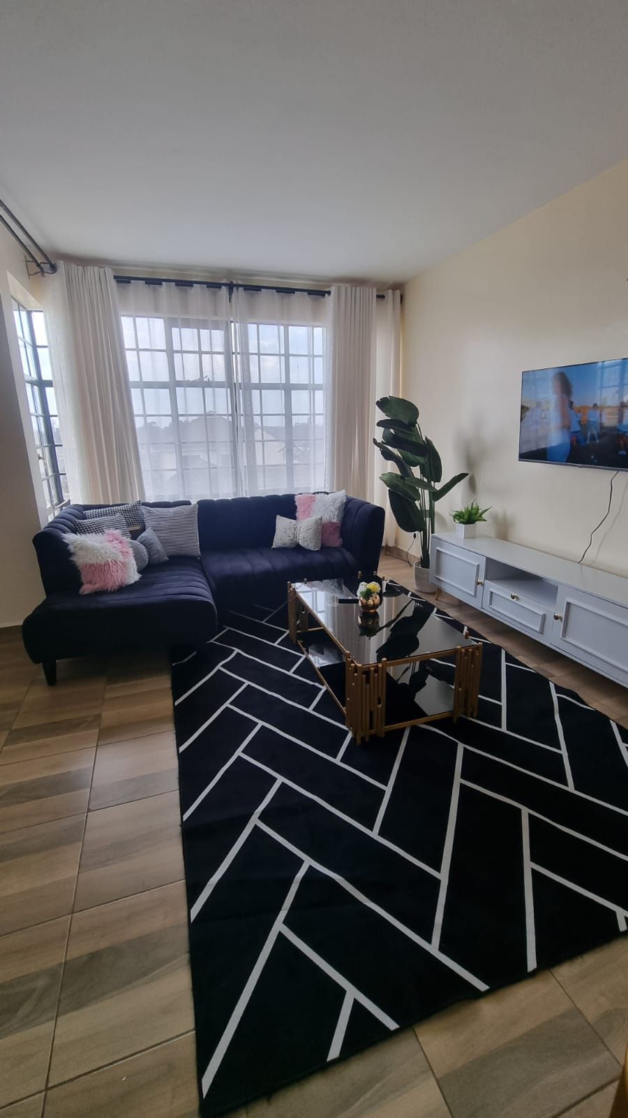 A living room with a sofa, a coffee table, and a TV on the wall.
