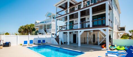 A modern multi-story building with a swimming pool and lounge chairs.