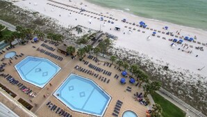 A resort with multiple swimming pools, sun loungers, and a beach area.