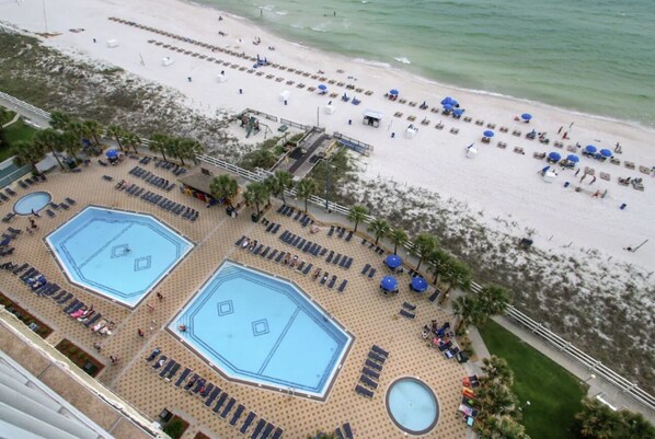 A resort with multiple swimming pools, sun loungers, and a beach area.