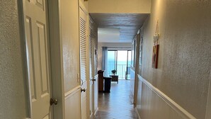 A hallway with a tiled floor, white walls, and a door on the left.