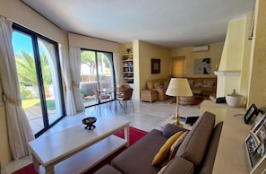 A spacious living room with a large sliding glass door leading to a patio, a sofa, a coffee table, and a bookshelf.