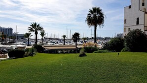 Uma marina com vários barcos, palmeiras e um edifício com telhado plano.