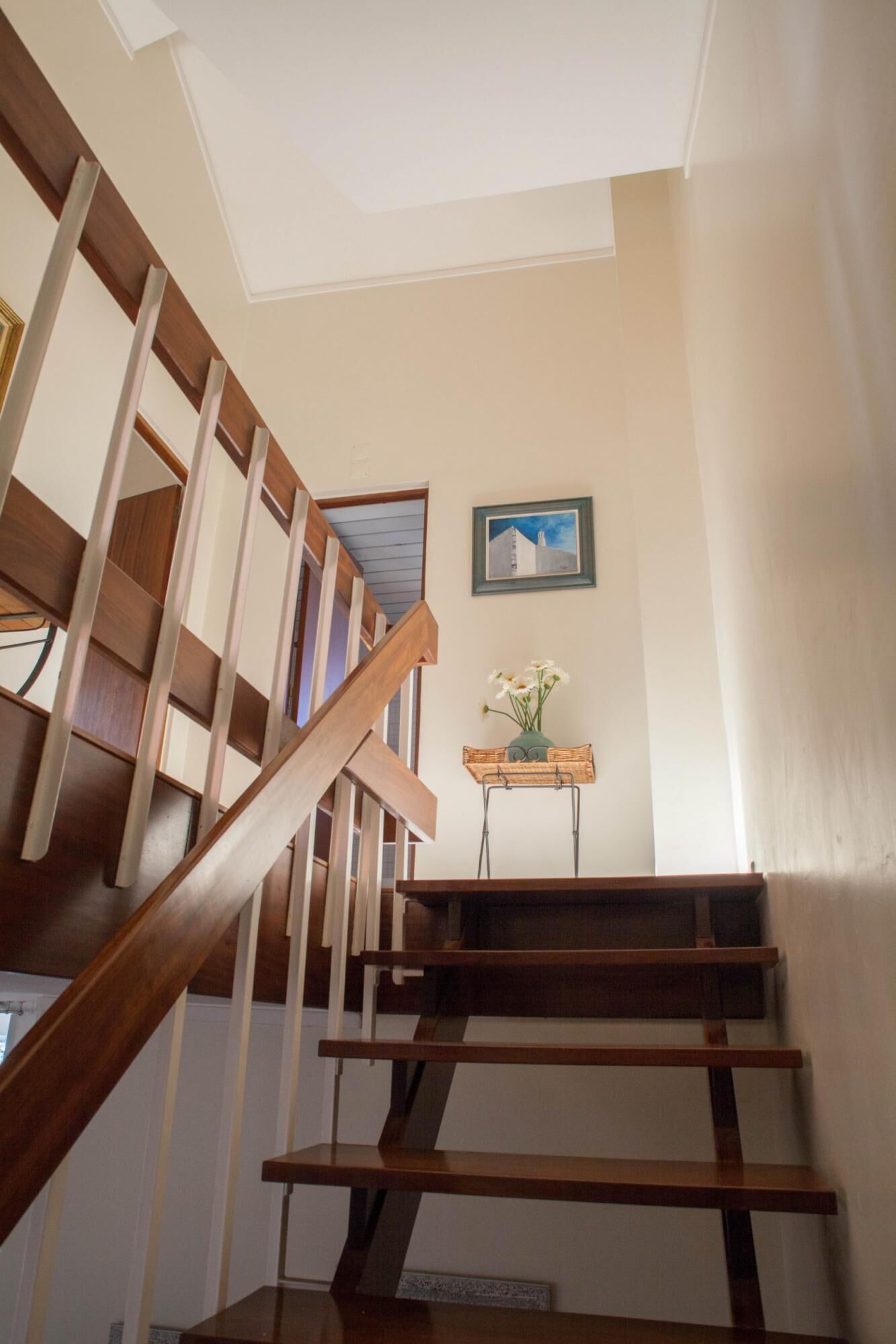 Eine Holztreppe mit einem kleinen Tisch, auf dem eine Blumenvase steht.