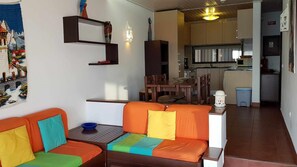 A cozy living area with a sofa set, a dining table, and a kitchen in the background.