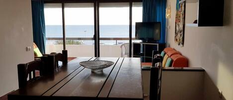 A room with a wooden table, chairs, a TV, and a sofa.