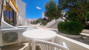 Eine Terrasse mit weißer Gartenmöbeln, einer Treppe und Topfpflanzen.