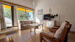 Un salon moderne avec un canapé, une table basse, un téléviseur et une plante.