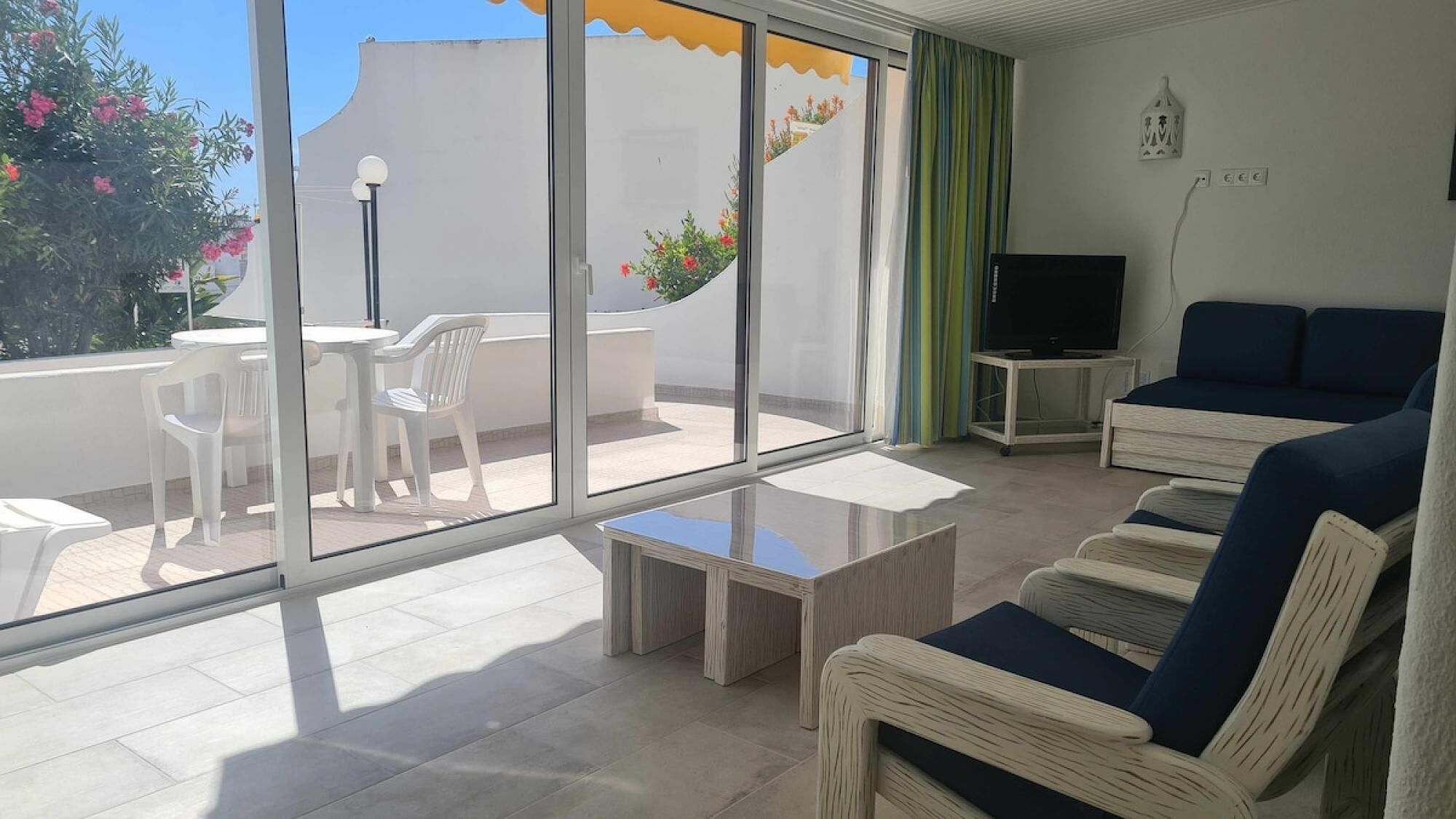 A modern living room with a sofa, a TV, and a balcony with a table and chairs.