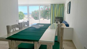 Una stanza con un tavolo da pranzo, sedie, una TV e vista sull'esterno.