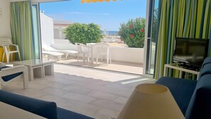 Un soggiorno moderno con un balcone, arredamento bianco e una televisione.