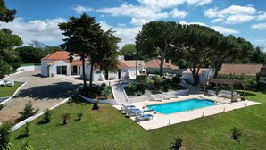 Uma villa moderna com piscina, rodeada por vegetação exuberante e um céu azul límpido.
