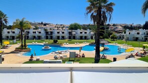 A resort with a large swimming pool surrounded by palm trees and sun loungers. - Green and Blue View Apartment Albufeira by Rentals in Algarve (Albufeira)