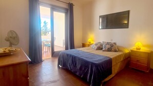 A bedroom with a bed, two bedside lamps, a fan, and a view of the outside. - Albufeira Balaia Mar e Sol (Albufeira)
