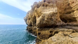 A coastal cliff with a rugged, rocky surface and a clear view of the ocean. - Albufeira Balaia Mar e Sol by Rentals in Algarve (Albufeira)