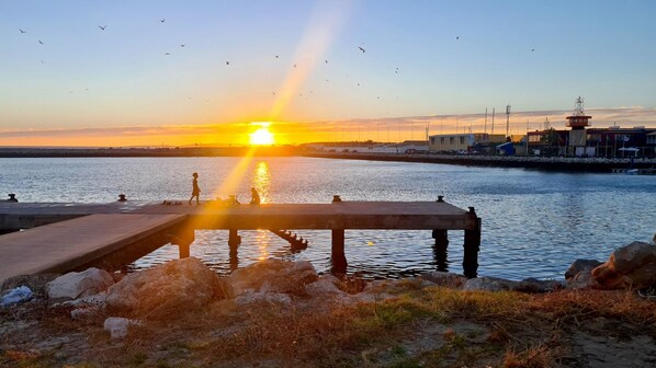 A sunset over a calm body of water with a pier extending into the water.