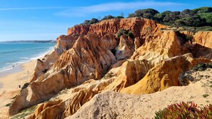 A coastal landscape with a sandy beach and rocky cliffs.