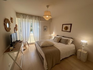 Ein Schlafzimmer mit Bett, Nachttisch, Lampe und Schreibtisch mit Computer.