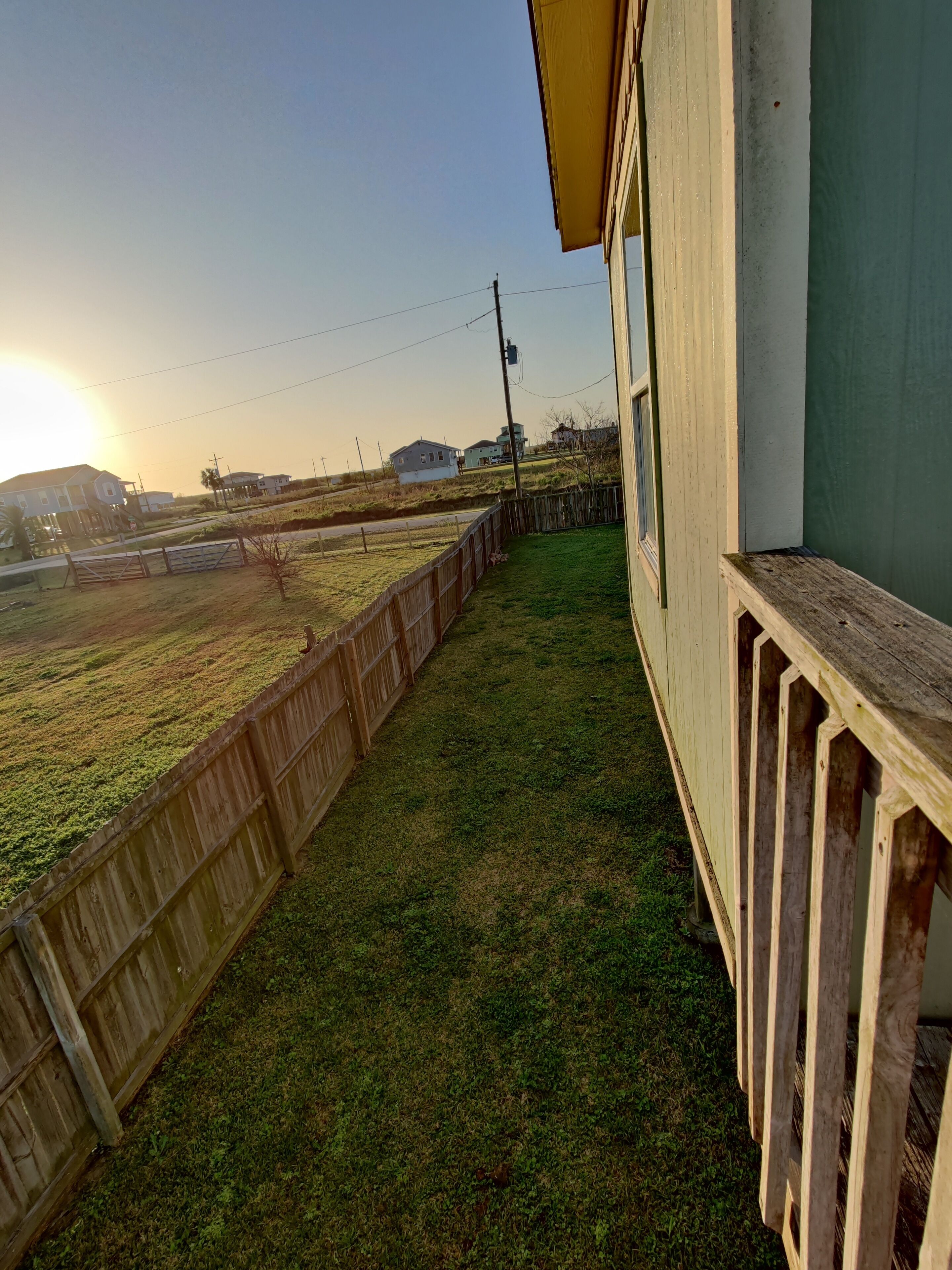 A balcony with a view of a grassy area and distant houses.