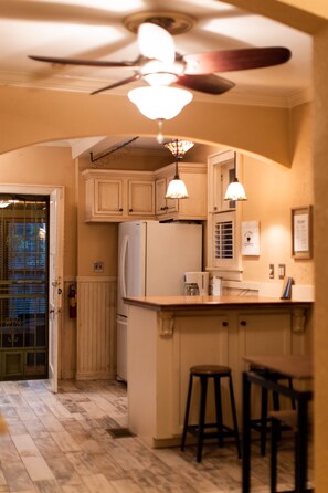 Kitchen area with central island, refrigerator, and sink, featuring pendant lights and a ceiling fan.