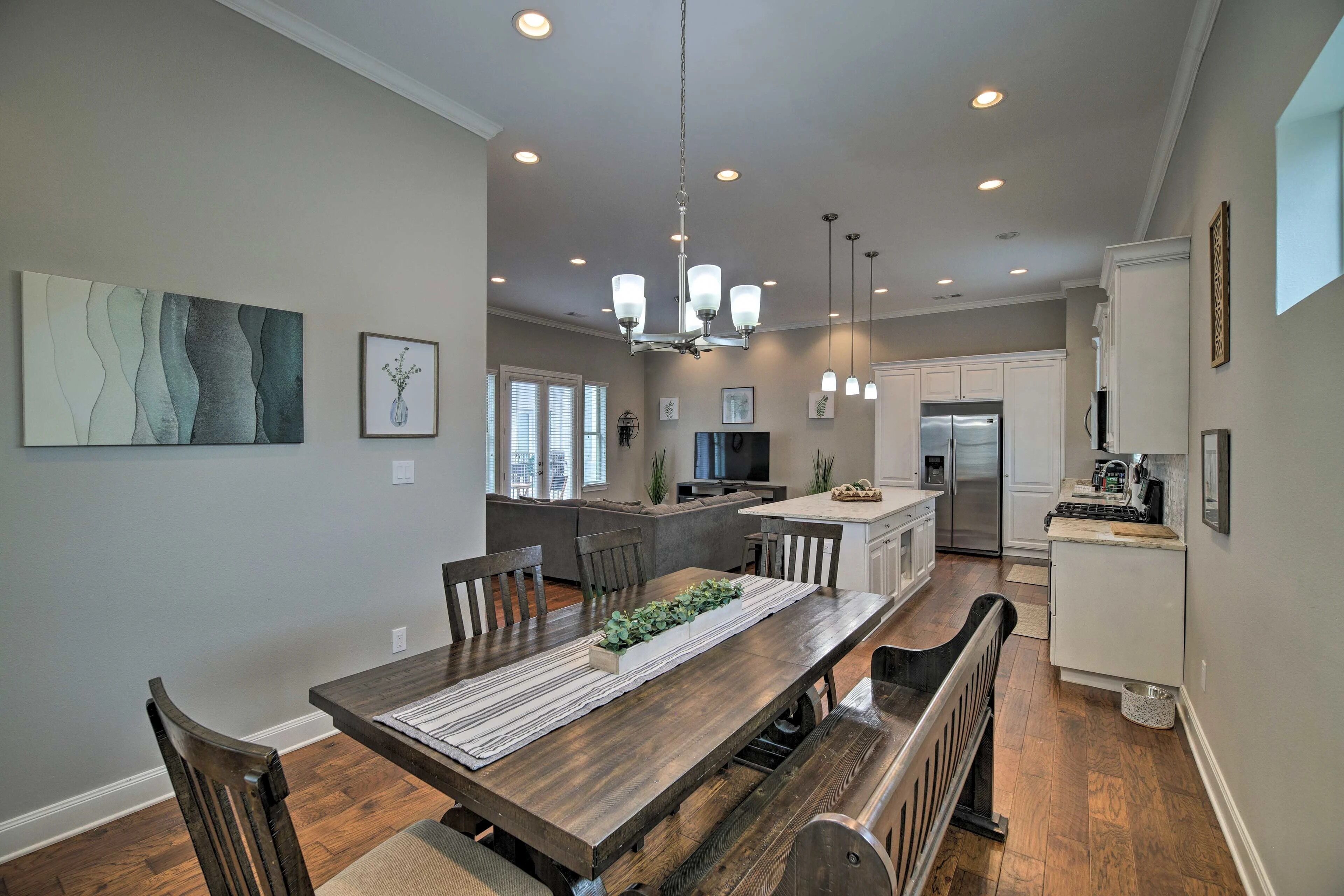 A modern kitchen with a dining area, featuring a wooden table, chairs, and a central island.