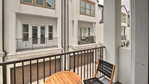 Ein Wohngebäude mit Balkon, einem Holztisch und einem Stuhl.